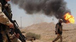 A U.S. soldier stands guard duty near a burning oil well in the Rumaila oil field in 2003. Photo Credit: Arlo K. Abrahamson / U.S. Navy