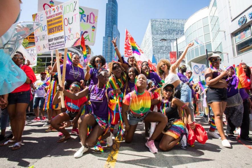 Participants in the pride march in Toronto with 'Fight for 15' placards.