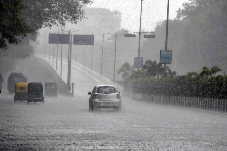 Vehicles move on the road during the heavy rainfall, in Surat on Sunday.