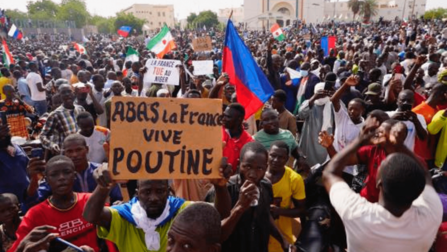 Nigeriens participate in a march called by supporters of coup leader Gen. Abdourahmane Tchiani in Niamey, Niger, July 30, 2023. Poster reads: ”Down with France, long live Putin.”