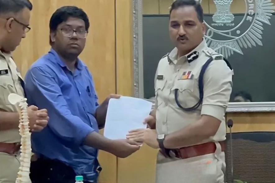 Kolkata Police Commissioner Vineet Goyal being given a memorandum demanding his resignation, symbolised by a spine placed on his desk.